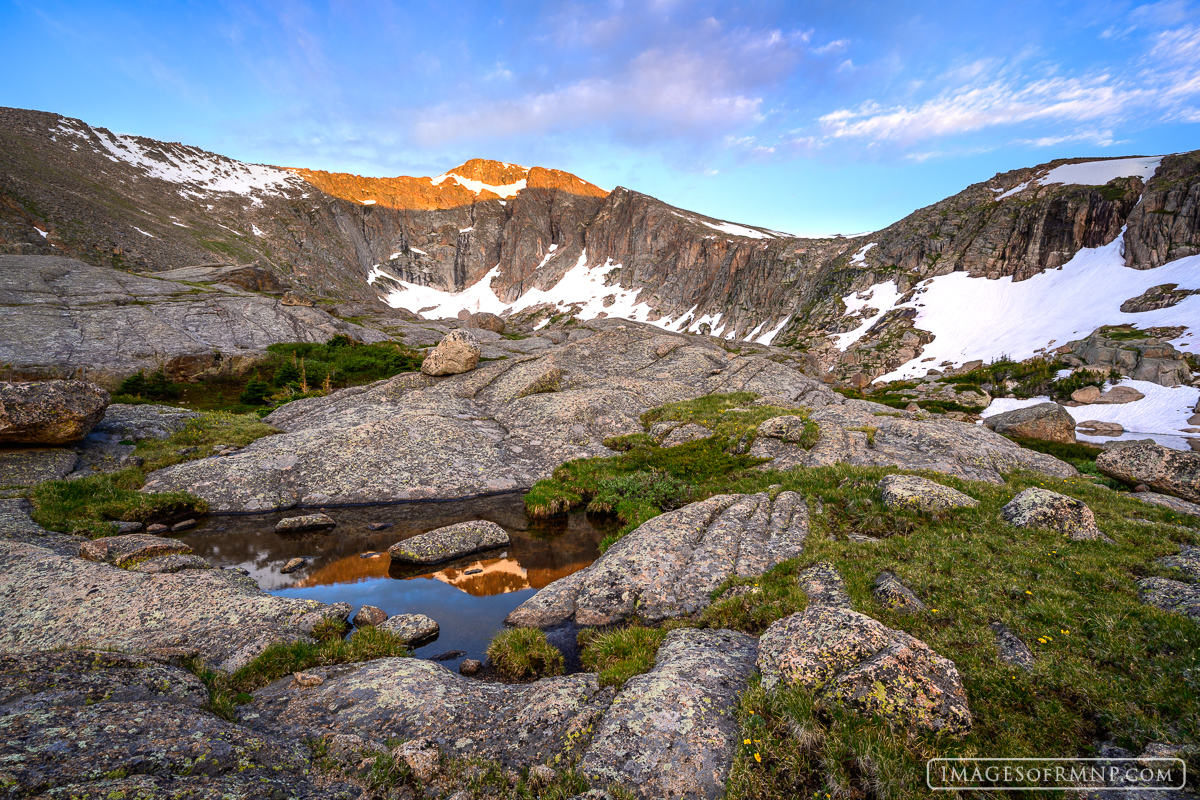 High in the Mummy Range of Rocky Mountain National Park the day begins with first light on Fairchild Mountain, which reflects...