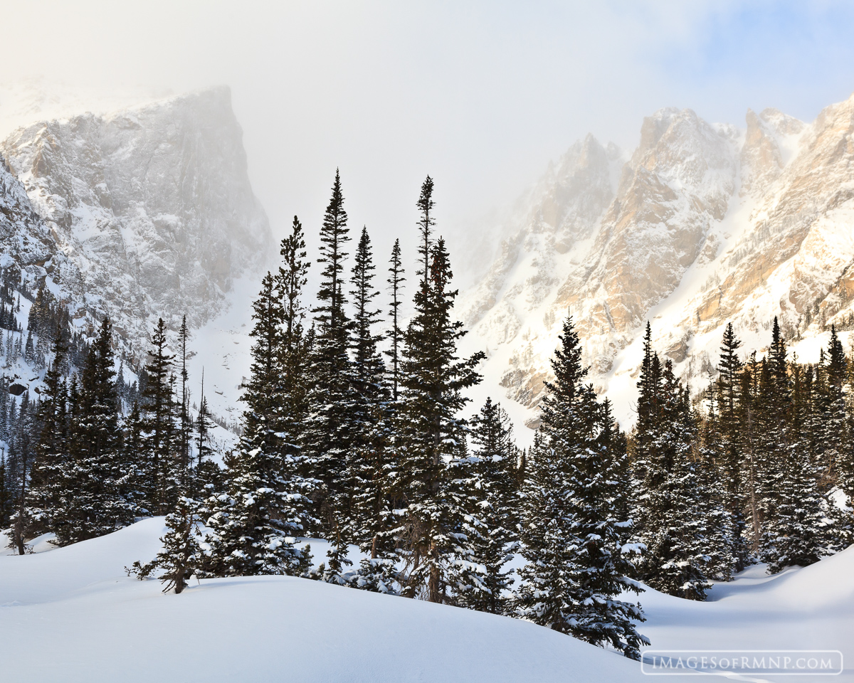 This is the typical winter view near Dream Lake. Hallett Peak and Flattop Mountain peek through the blowing clouds while deep...