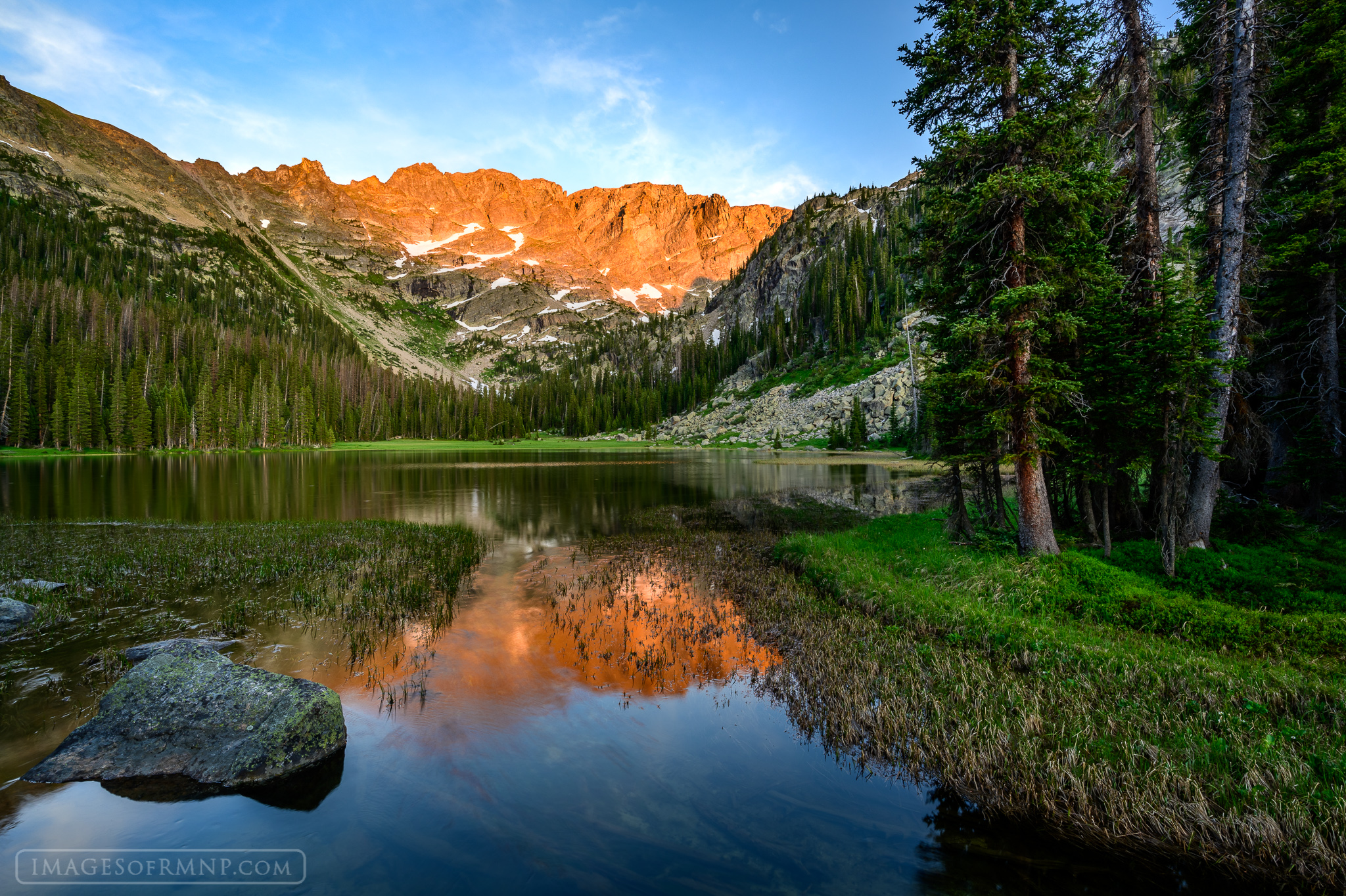 As the day comes to an end the Continental Divide glows brightly, reflecting on the outlet of a small lake in the backcountry...