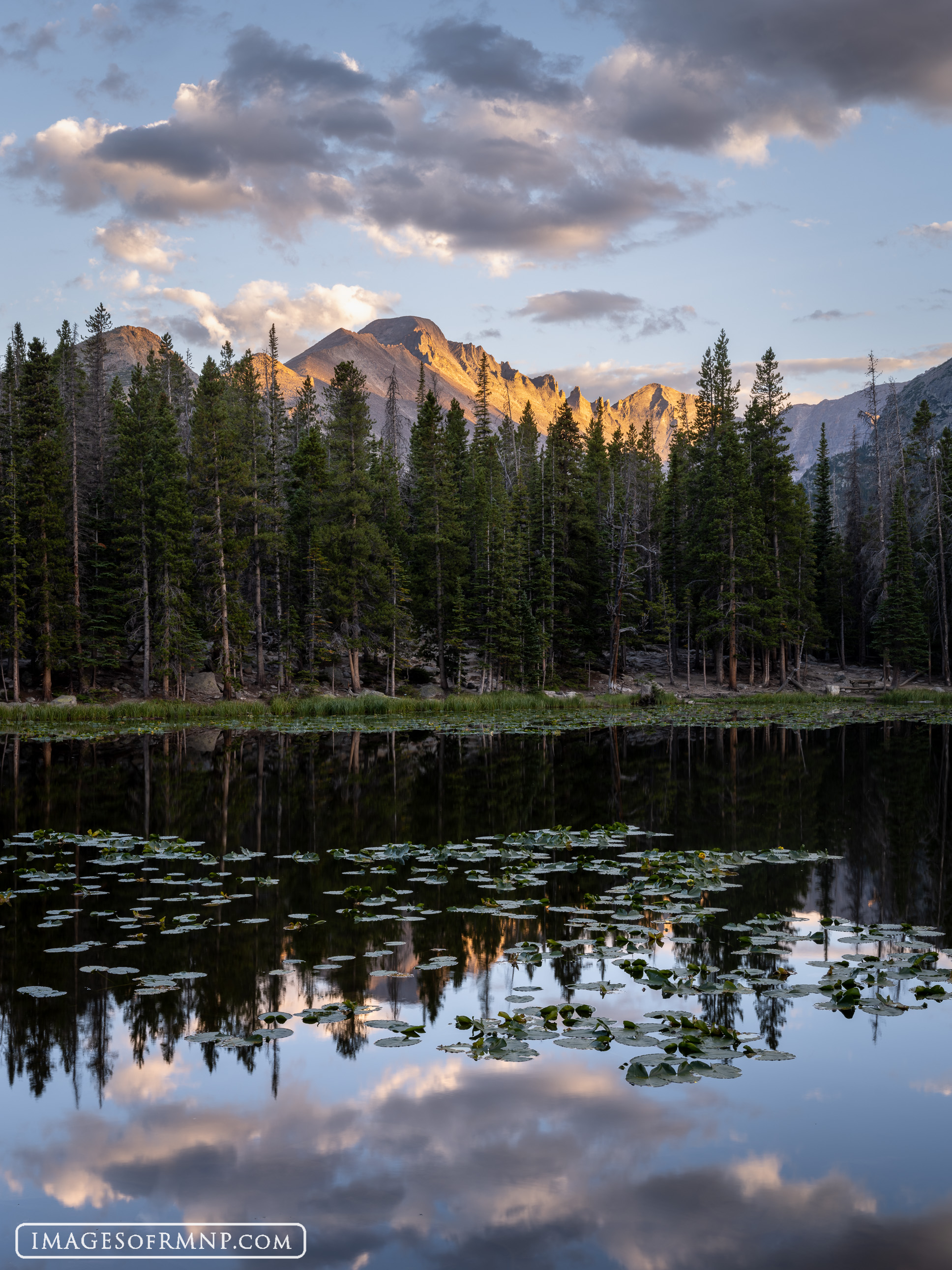 The blocky west face of Longs Peak catches the last light of the day over the calm waters of Nymph Lake.