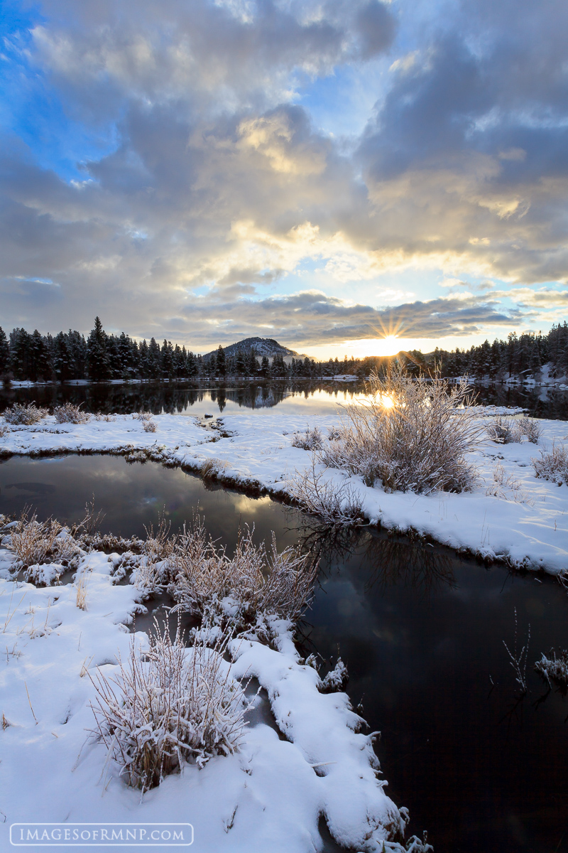 The sun rises over Sprague Lake on a snowy Sprague Lake on a beautiful May morning.