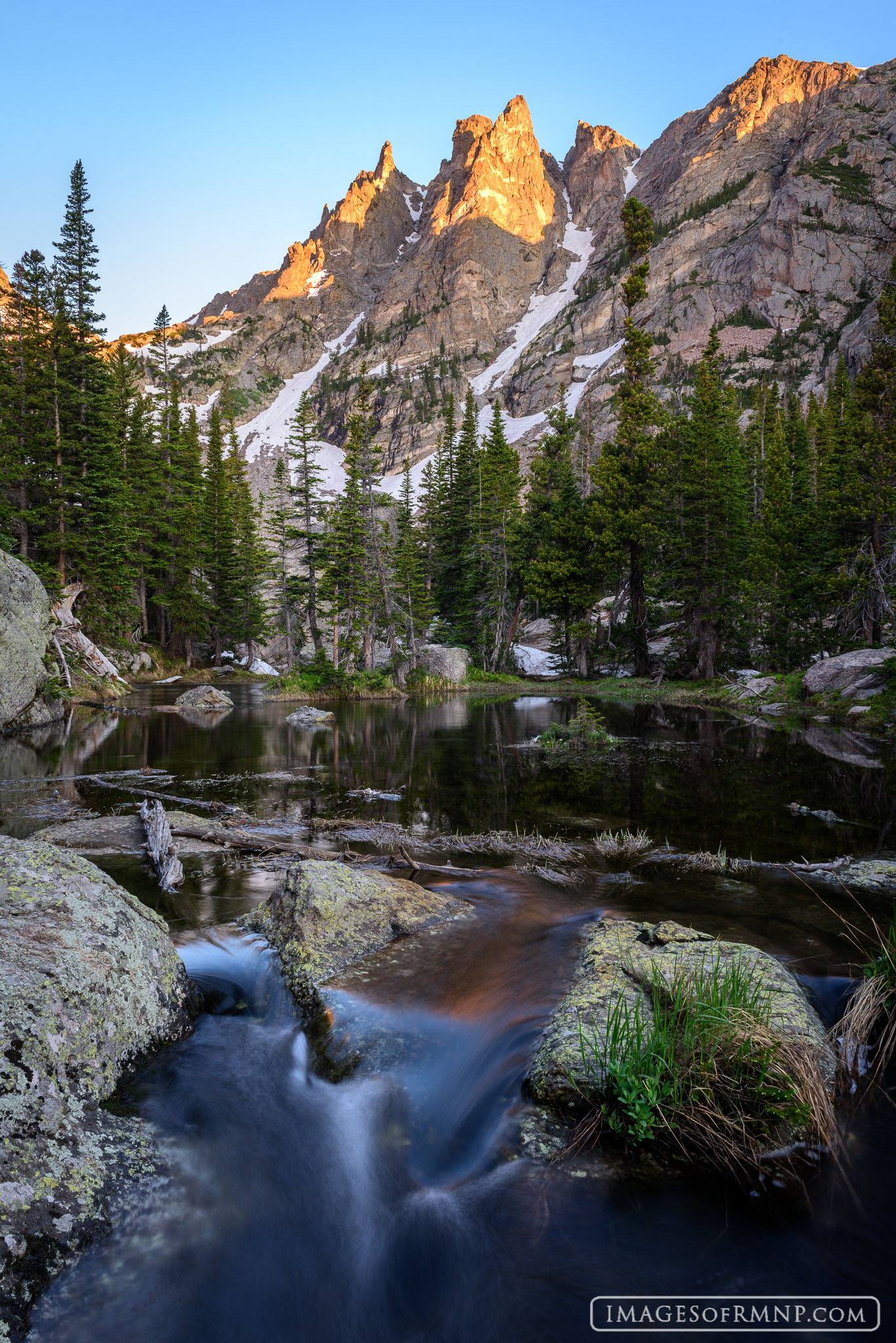 A beautiful summer morning below Emerald Lake provides a stunning view of Flattop Mountain lit by the first rays of the sun....