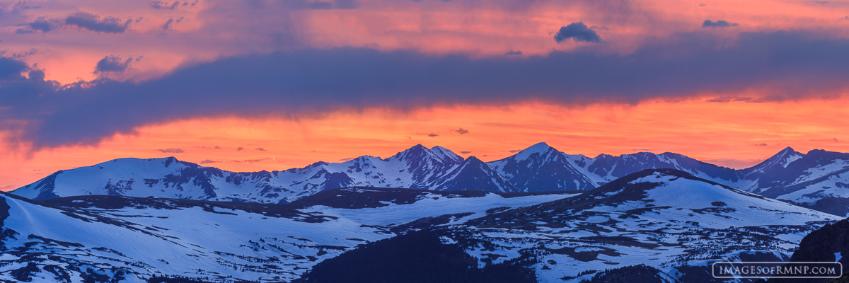 Snow covers the Never Summer Mountains on a beautiful May evening while the recently descended sun warms the sky with its gentle...